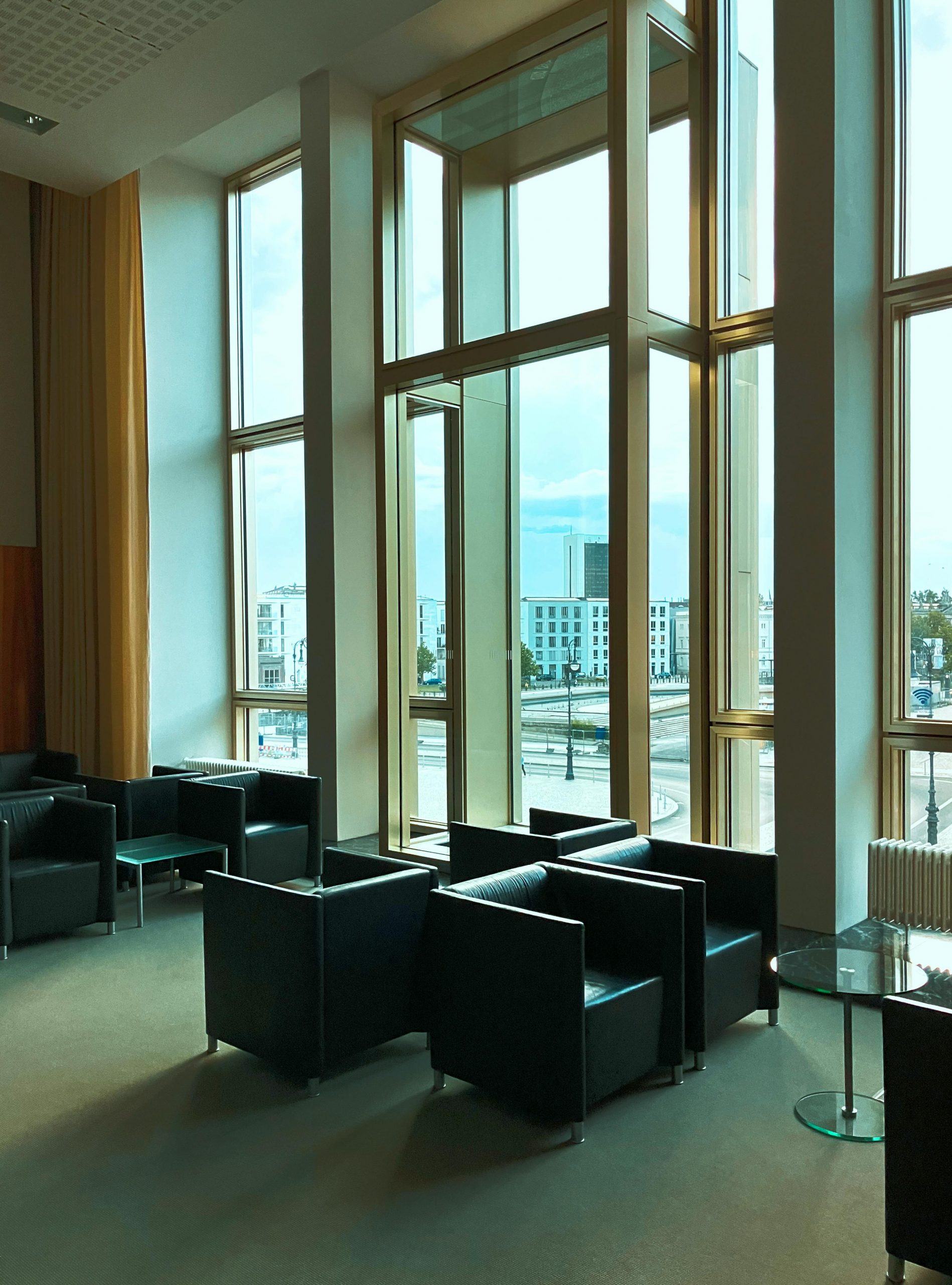 Spacious contemporary lobby with panoramic windows and stylish black chairs in Berlin.