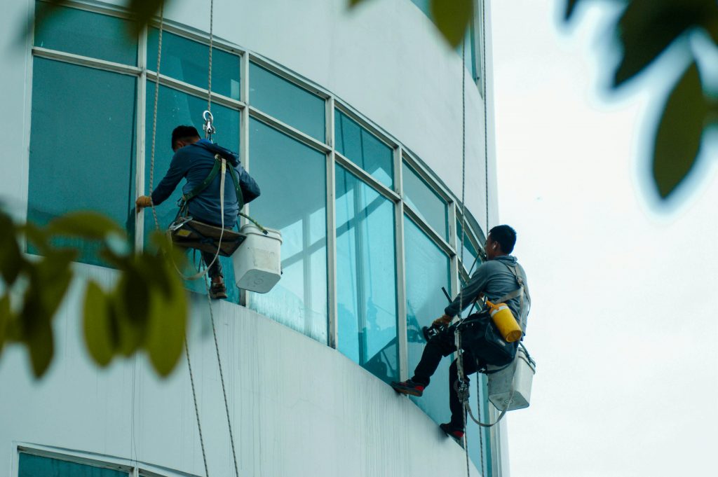 Window cleaners suspended on ropes clean a high-rise building's glass exterior.